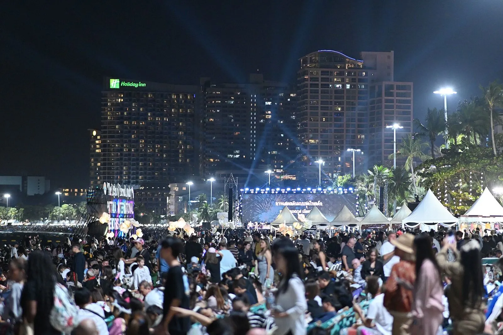 Multitud reunida de noche frente a un escenario iluminado al aire libre