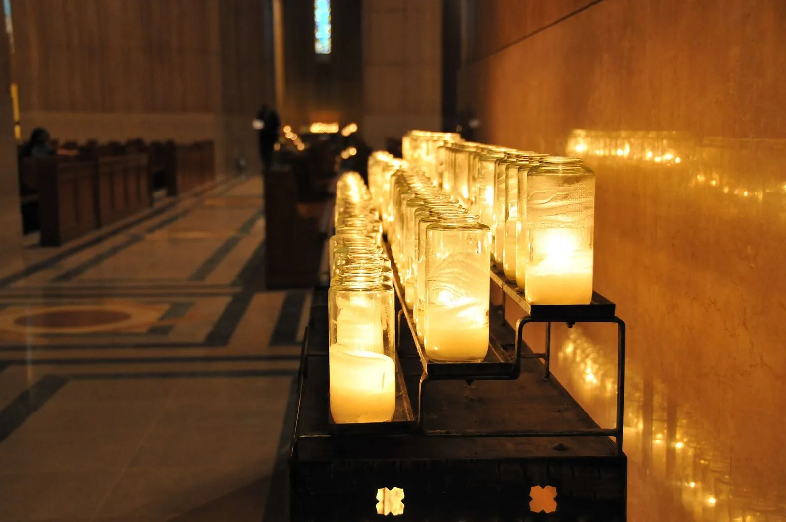 Velas de oración encendidas en la penumbra de una iglesia