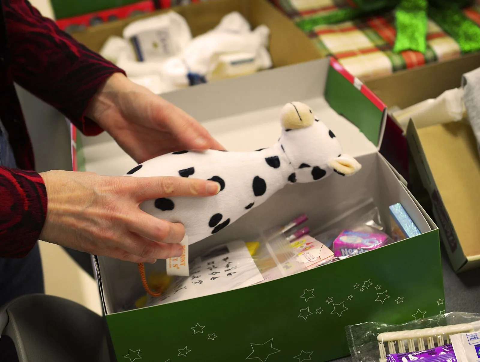 Manos de una voluntaria llenando una caja de zapatos de Operation Christmas Child con un peluche y material escolar (base aérea de Yokota, Japón, noviembre de 2016)